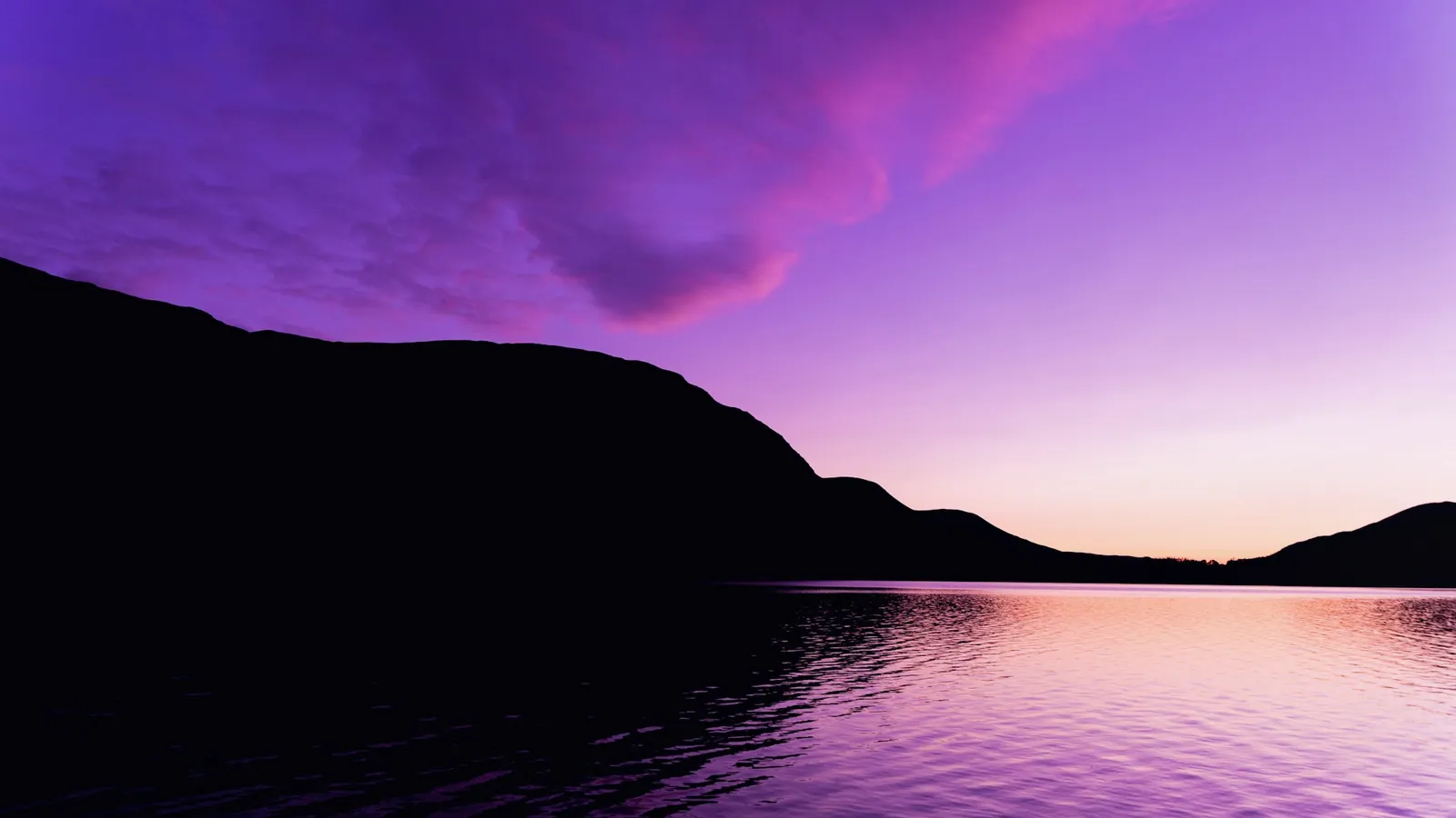 Lac au crépuscule sous un ciel violet strié de rose, montagne en ombre chinoise