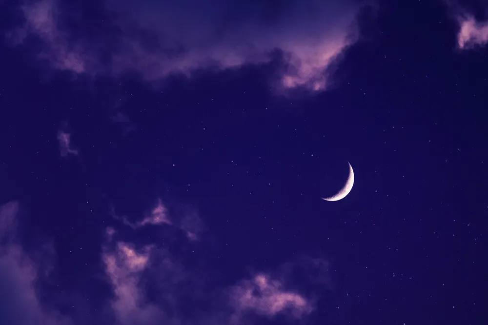 Croissant de lune dans un ciel violet et nuageux