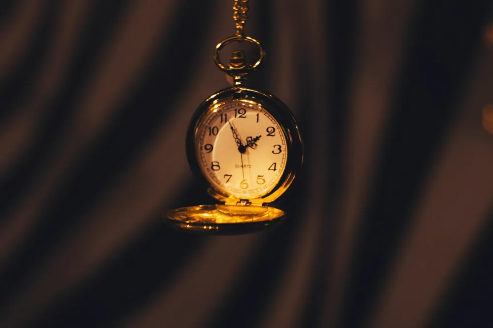 Montre de poche en laiton suspendue à sa chaîne, cadran éclairé sur fond sombre